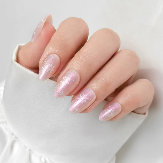 Shimmery pink almond press-on nails with white snowflake accents, soft gel finish