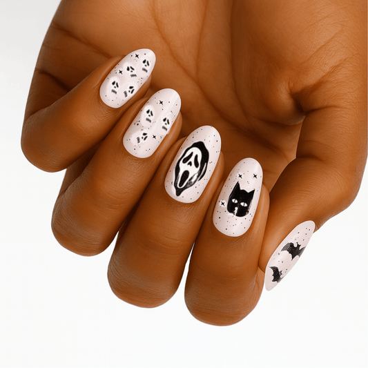 Hand wearing Halloween nail wraps with black cats, ghosts and Scream designs on white base