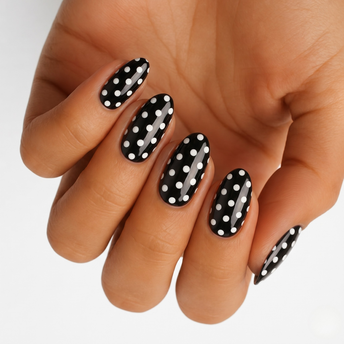 Glossy black nail wraps with white polka dot pattern, almond shape