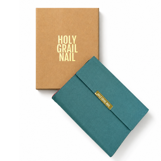 Teal faux-leather nail wrap storage clutch with gold logo plate, beside kraft gift box.