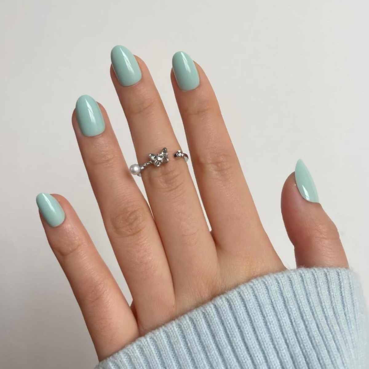 Short oval soft gel press-on nails in solid sage green with a glossy finish