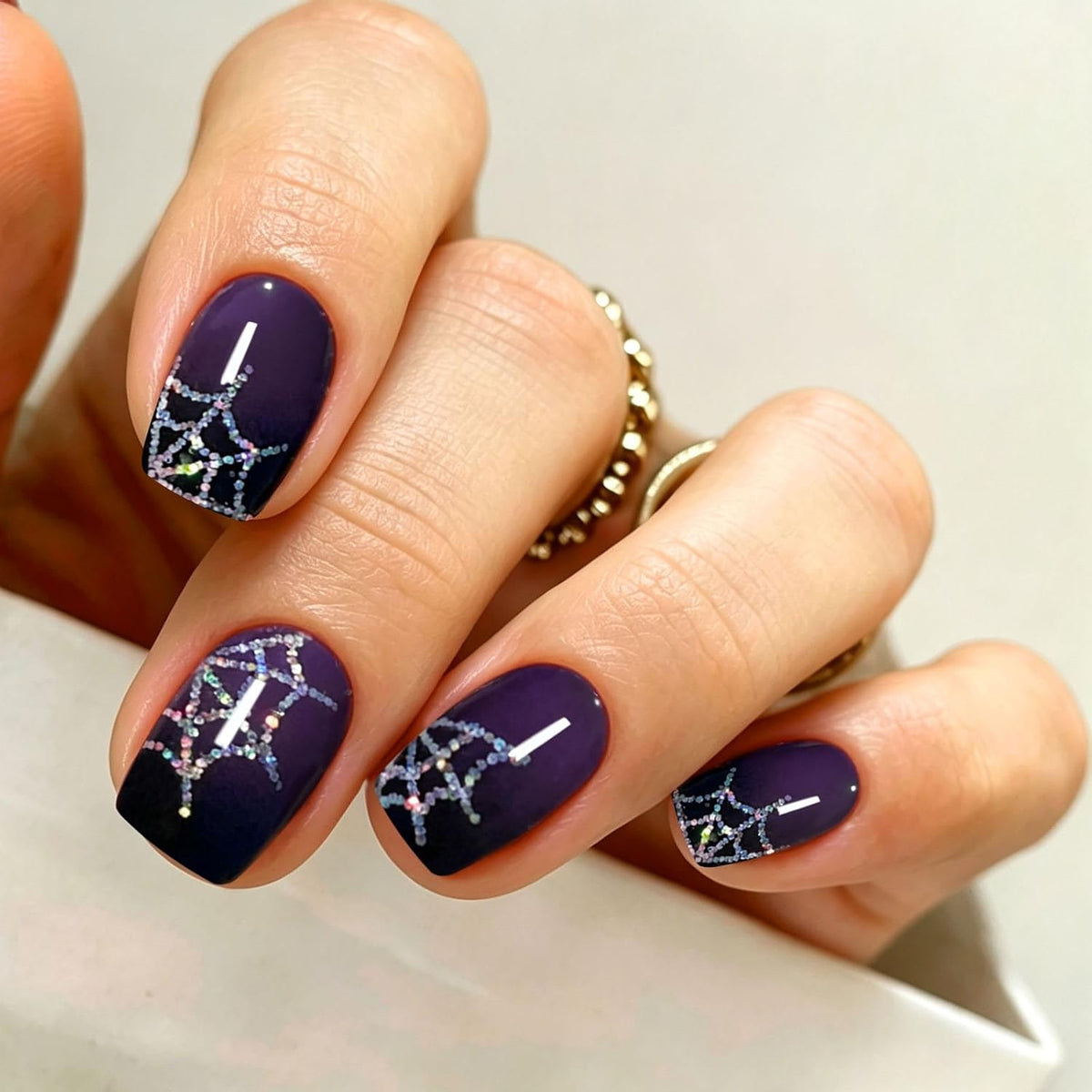Deep purple semi-cured gel nail wraps with glittery silver spiderweb Halloween design.