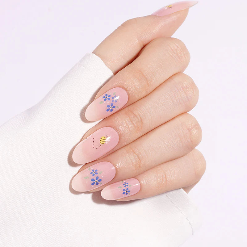 Sheer pink semi-cured gel nail wraps with blue floral and bee design