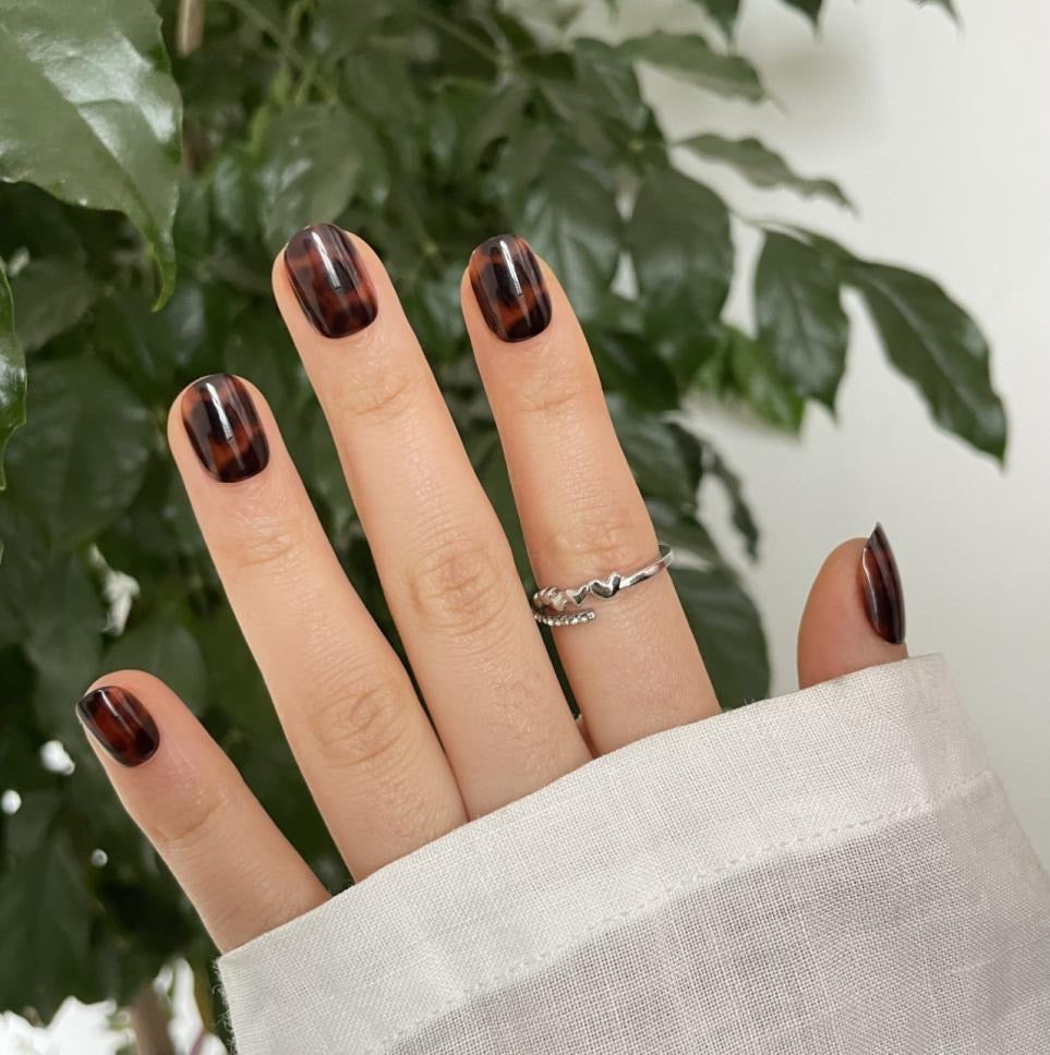 Short round press-on nails in a brown tortoiseshell pattern with glossy finish