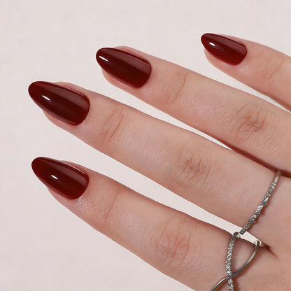 Dark burgundy glossy soft gel press-on nails in a short almond shape