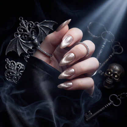 Champagne gold shimmer press-on nails, stiletto shape, on hand with gothic skull decor