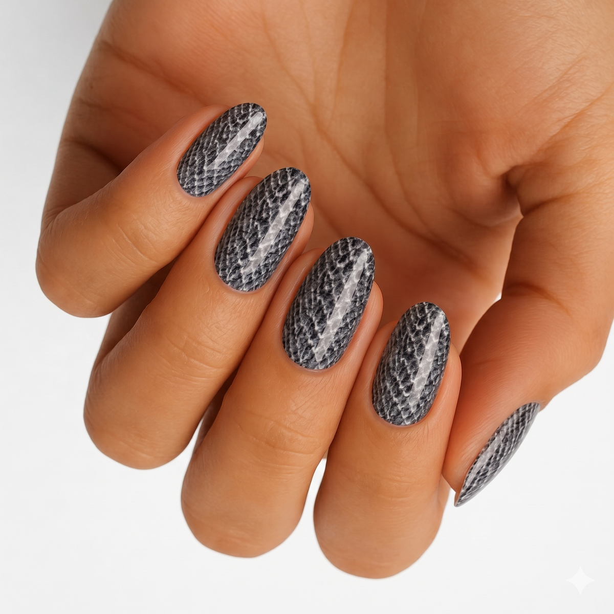 Grey and black snakeskin print nail wraps on almond-shaped nails.
