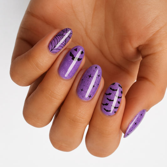 Purple glitter nail wraps with Halloween spiderweb, pumpkin, bat and star designs