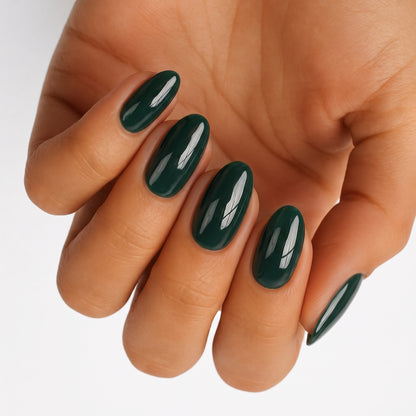 Glossy dark green nail wraps on an oval manicure, solid high-shine finish.