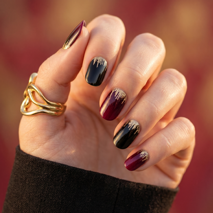 Semi-cured gel nail wraps in glossy black and burgundy with gold glitter drip design
