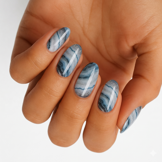 Blue-grey agate marble nail wraps with silver glitter accents, almond-shaped nails