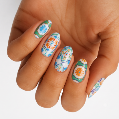 White nail wraps with Talavera-style tile florals in blue, green, and orange on almond nails.