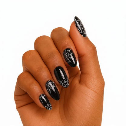Glossy black semi-cured gel wraps with white spiderweb design on almond-shaped nails.
