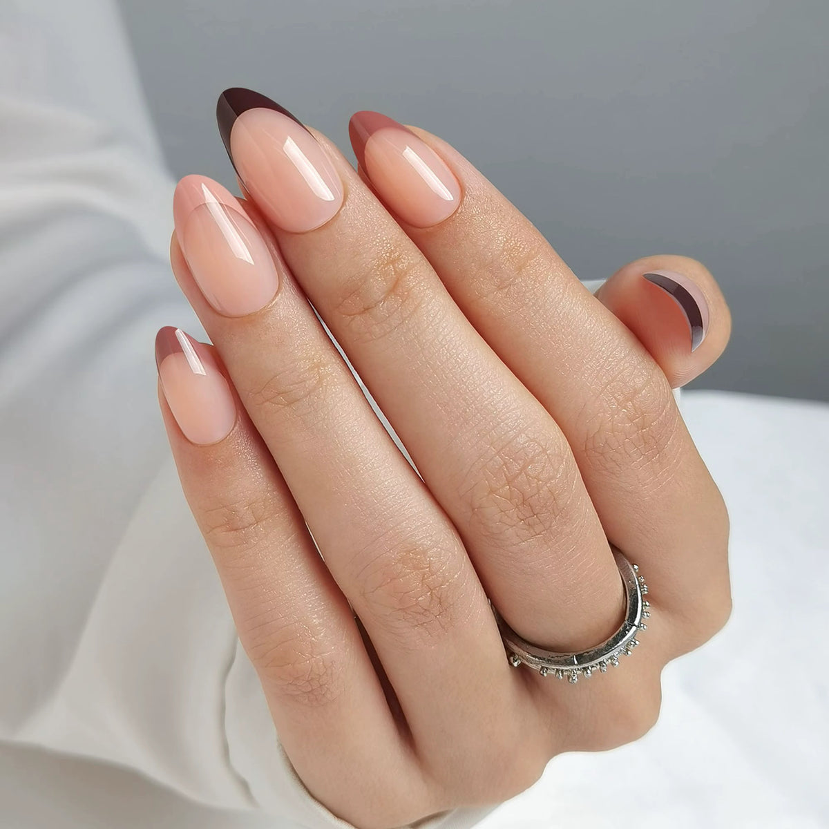 Glossy nude almond nails with deep burgundy French tip outline design