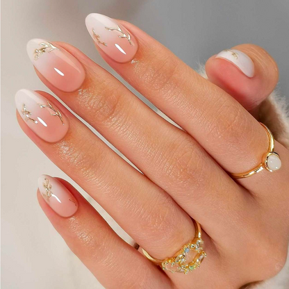 Glossy nude press-on nails with white French tips and gold branch accents