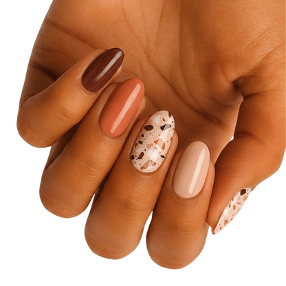 Glossy nail wraps in brown, terracotta, and nude with terrazzo speckled accent nails.