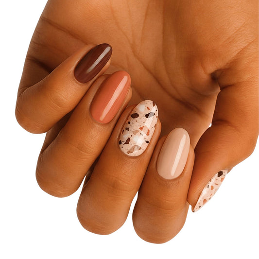 Glossy nail wraps in brown, terracotta, and nude with terrazzo speckled accent nails.