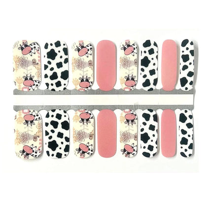 Nail wraps with cartoon cow print, black-and-white cow spots, and solid pink accent nails.