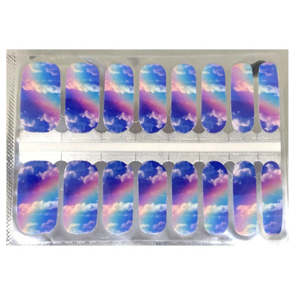 Nail wraps with blue sky, clouds and pastel rainbow design across nails