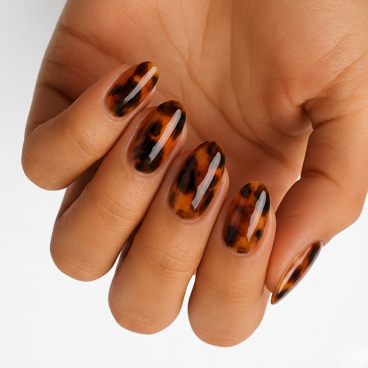 Glossy amber and black tortoiseshell pattern nail wraps on an almond-shaped manicure