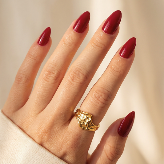 Deep red glossy soft gel press-on nails in a short almond shape, solid colour finish.