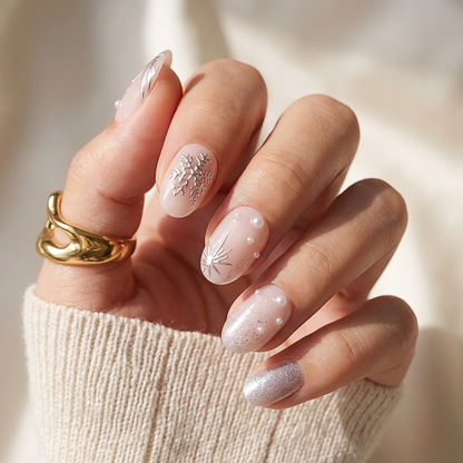 Nude press-on nails with silver snowflake art, glitter accent, and pearl details