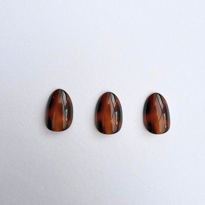 Glossy brown tortoiseshell pattern on extra short almond soft gel press-on nails
