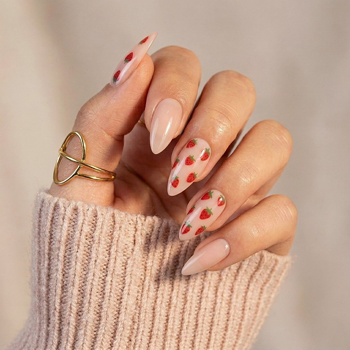 Sheer nude glossy press-on nails with red strawberry print, almond shape