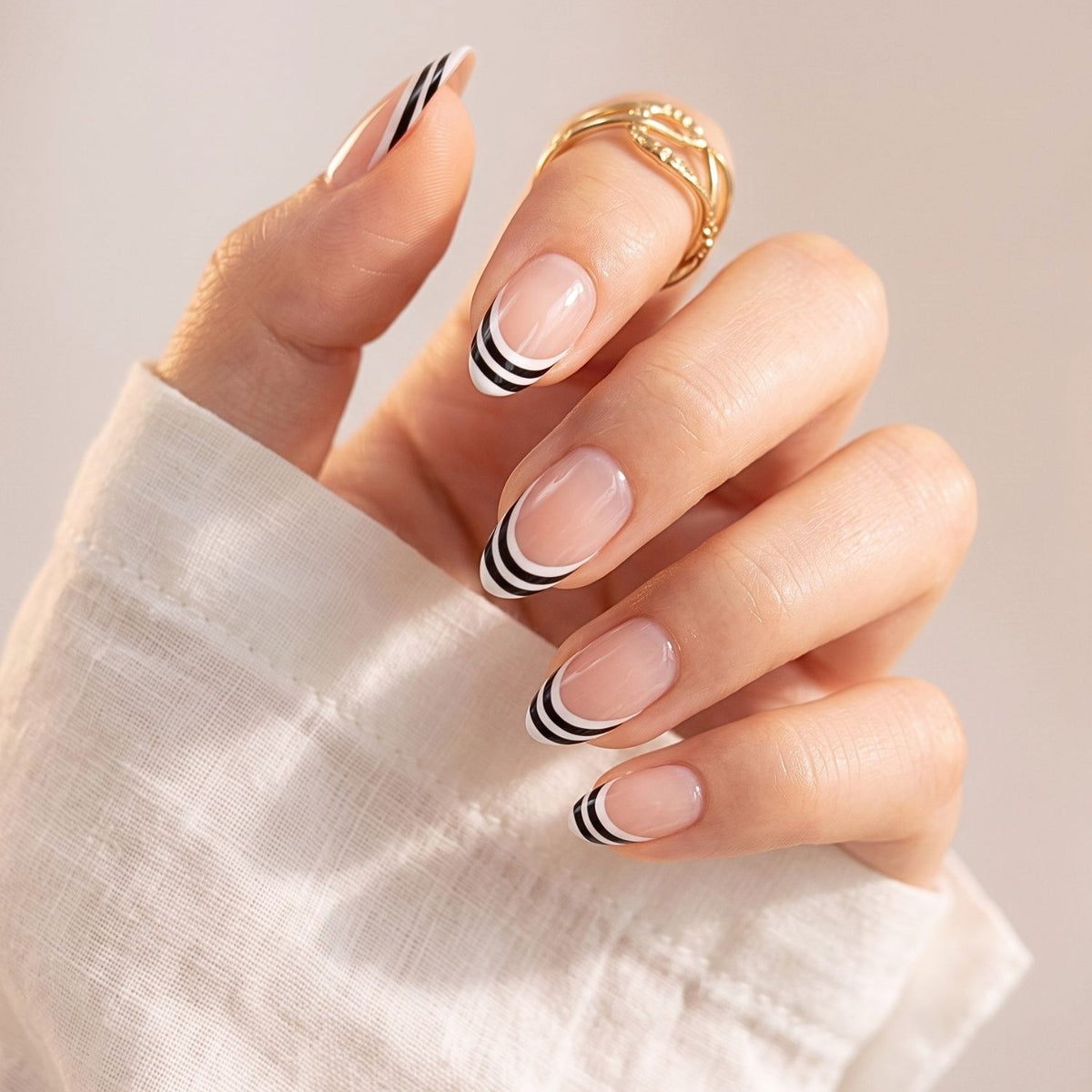 Short almond press-on nails, sheer nude base with white and black double French tips