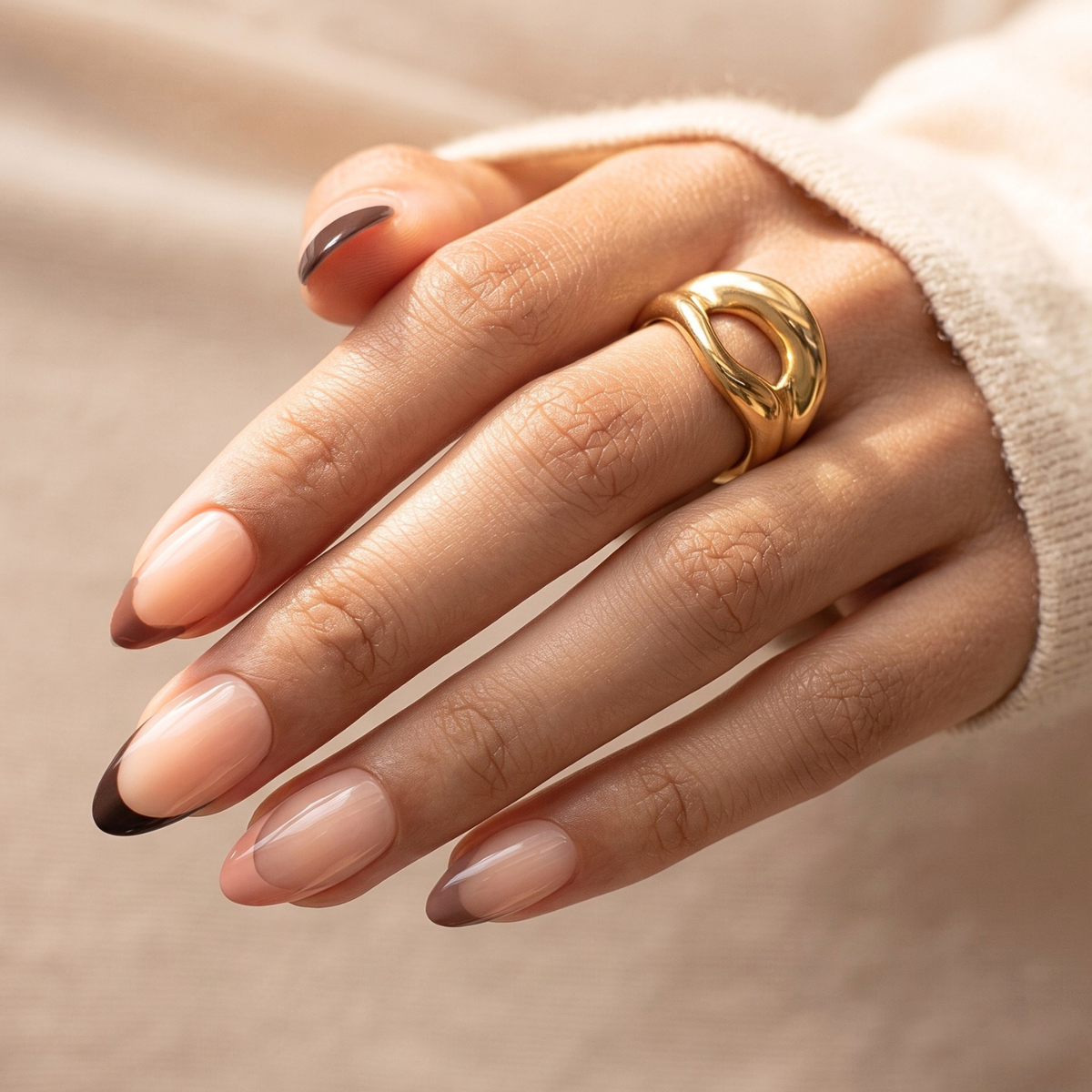 Short almond soft gel press-on nails, sheer nude with glossy brown French tips.