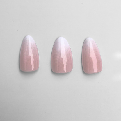 Glossy press-on nails, almond shape, pink-to-white ombre gradient design.
