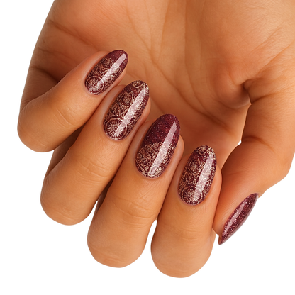 Burgundy glitter nail wraps with gold mandala lace pattern on almond-shaped nails