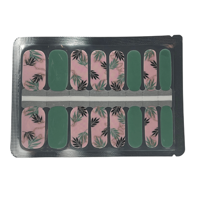 Nail wraps in pink marble with black and green fern leaf print, plus solid green accent nails