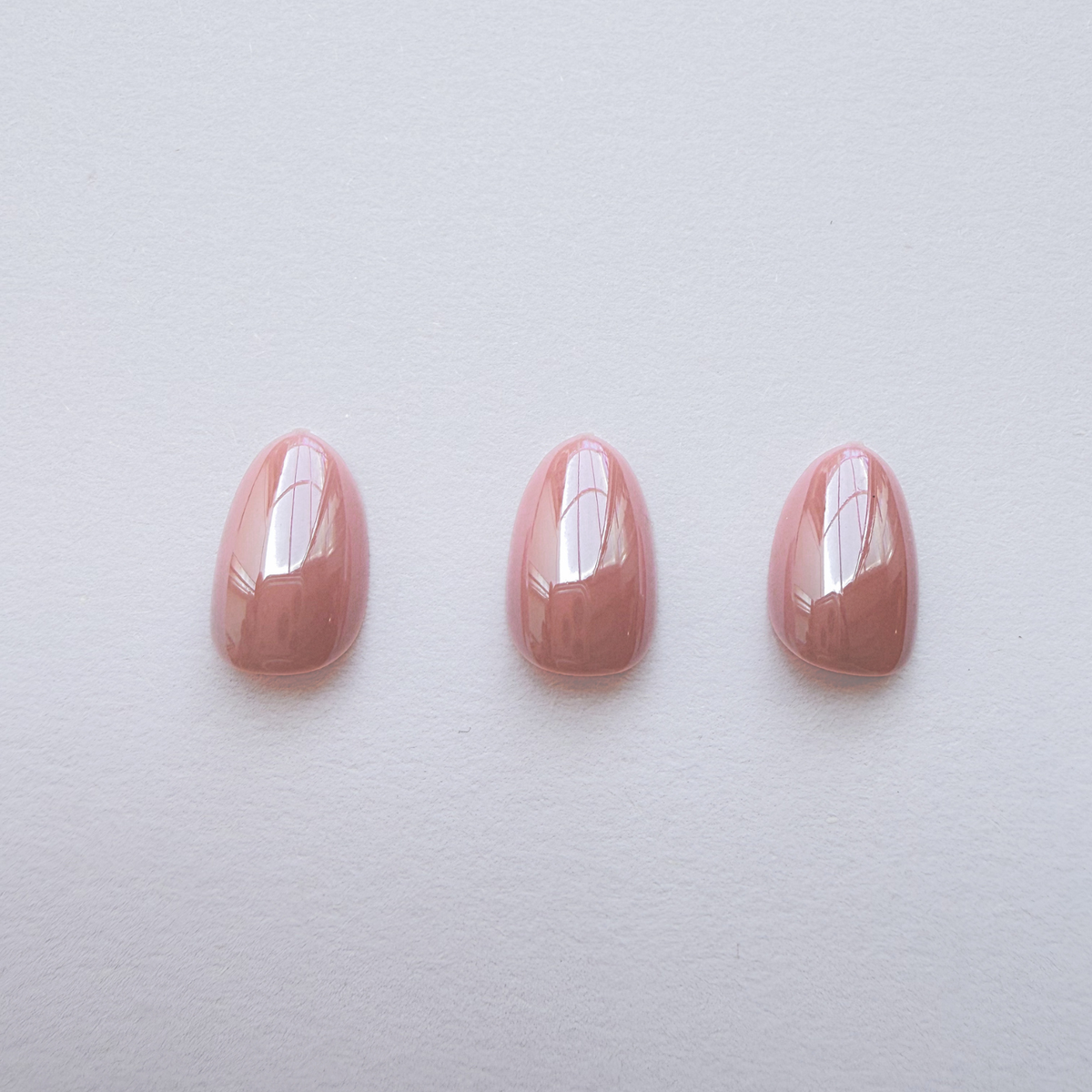 Glossy dusty pink soft gel press-on nails in a short rounded almond shape
