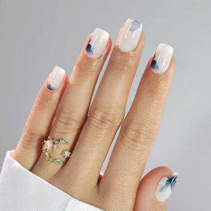 Sheer milky white press-on nails with abstract blue watercolor floral accents, glossy finish