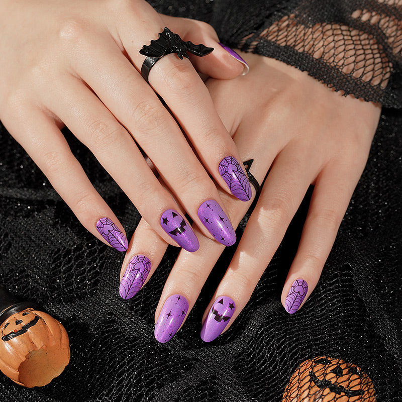 Purple nail wraps with black spiderweb, jack-o'-lantern face and star Halloween designs