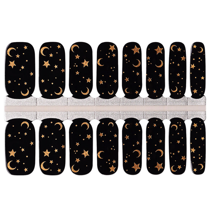 Black nail wraps with gold celestial moon and star design, glossy finish