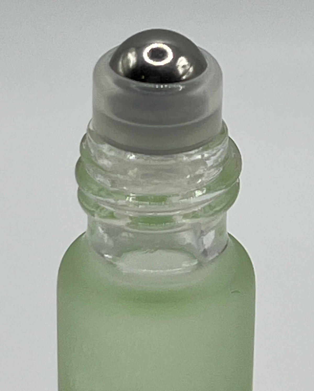 Close-up of green aloe cuticle oil rollerball applicator for precise nail treatment