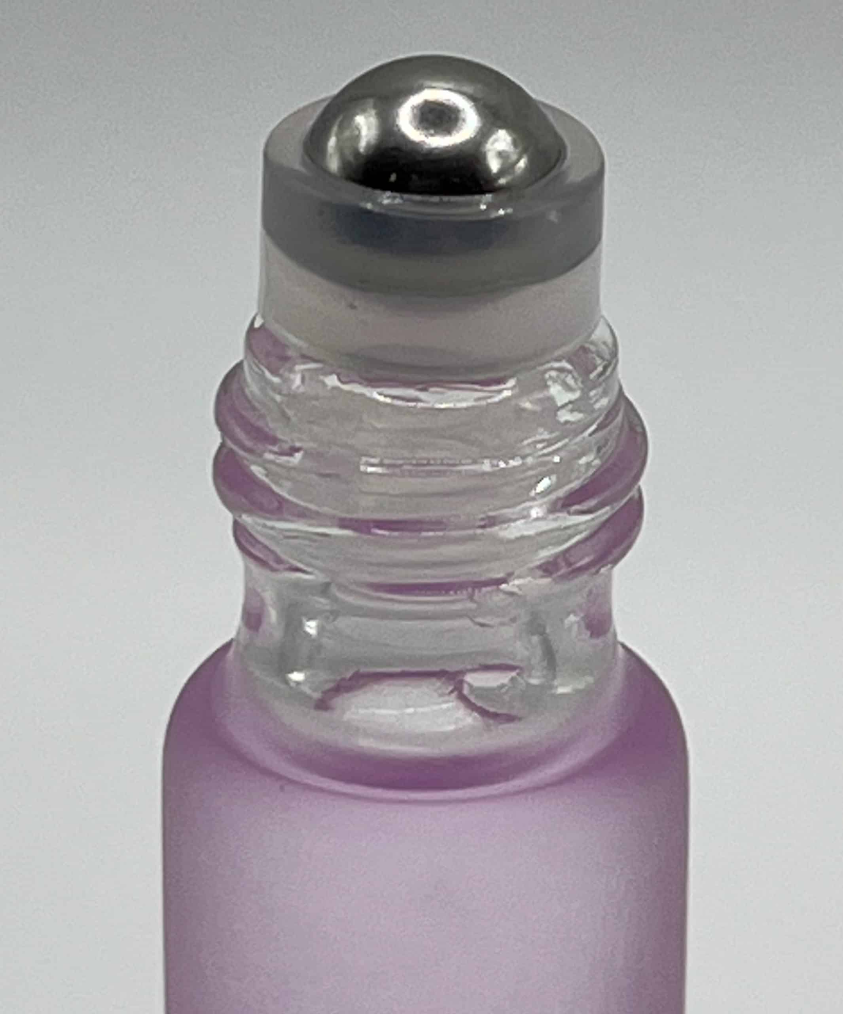 Close-up of lavender cuticle oil rollerball applicator with purple liquid for nail treatment