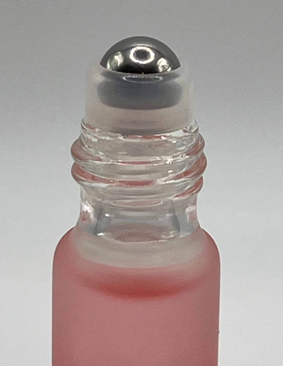 Close-up of rose cuticle oil roller ball applicator for precise nail treatment