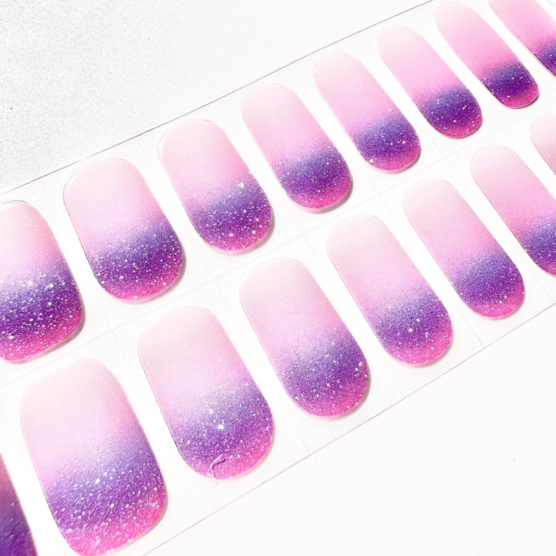 Close-up of purple pink glitter gradient gel nail wraps showing sparkly ombre nail art