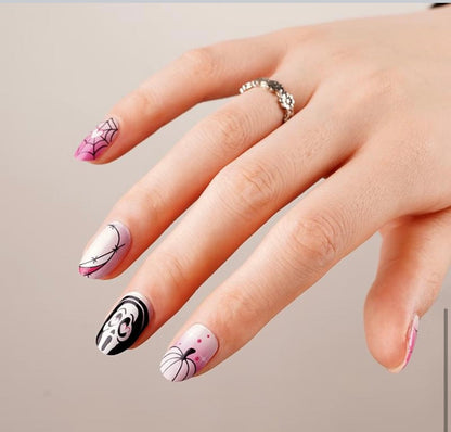 Hand wearing glow-in-the-dark Halloween nail wraps with gothic pink and black ghost patterns
