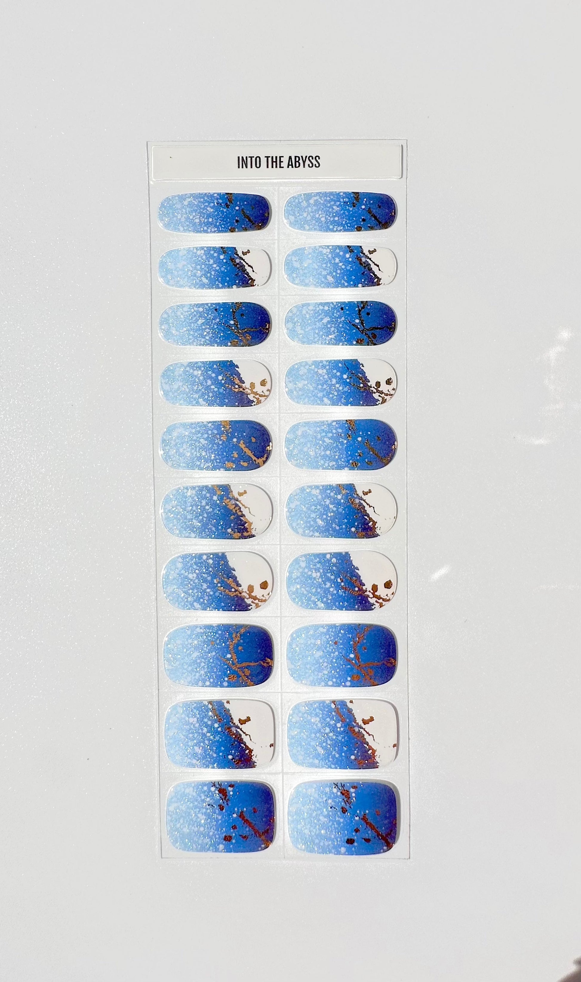 Into The Abyss semi-cured gel nail wraps featuring blue gradient with gold marble patterns on sheet