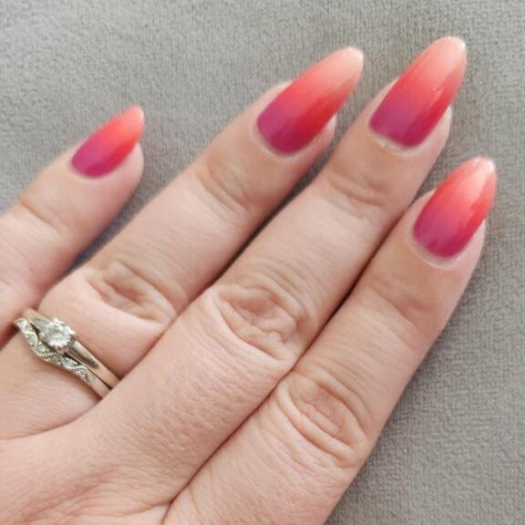 Pink coral ombre gel nail wraps with gradient effect on hand with ring