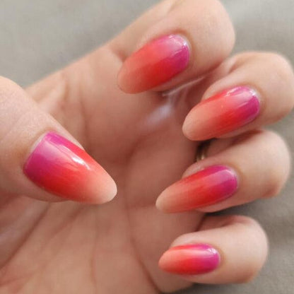 Pink coral ombre gel nail wraps on hand showing glossy gradient manicure