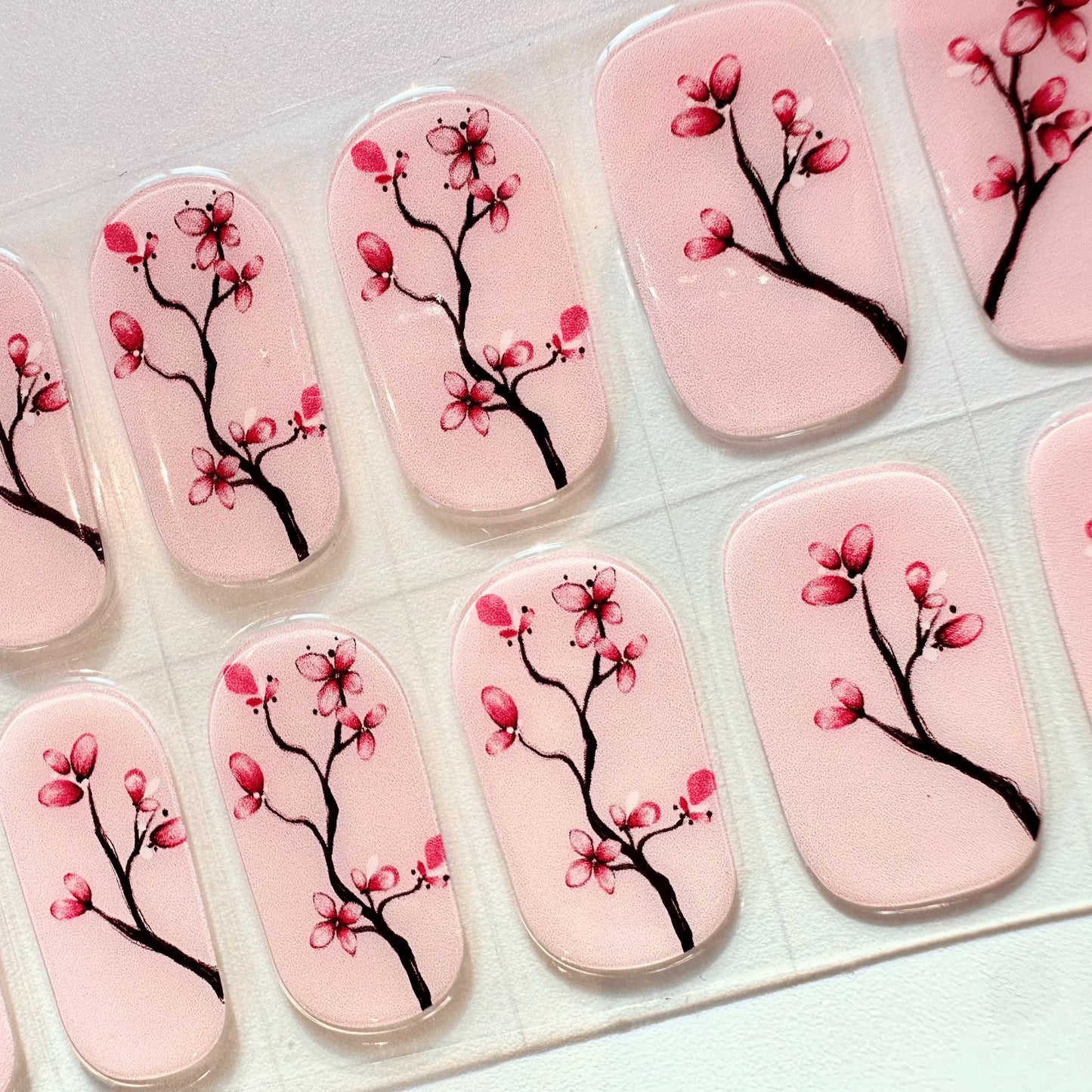 Cherry blossom gel nail wraps with pink floral pattern on clear backing
