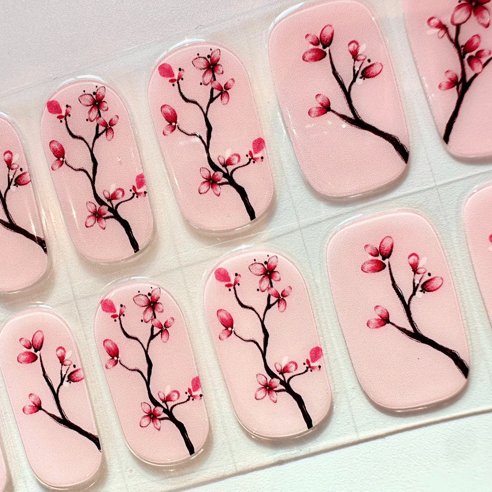 Cherry blossom gel nail wraps with pink floral pattern on clear backing