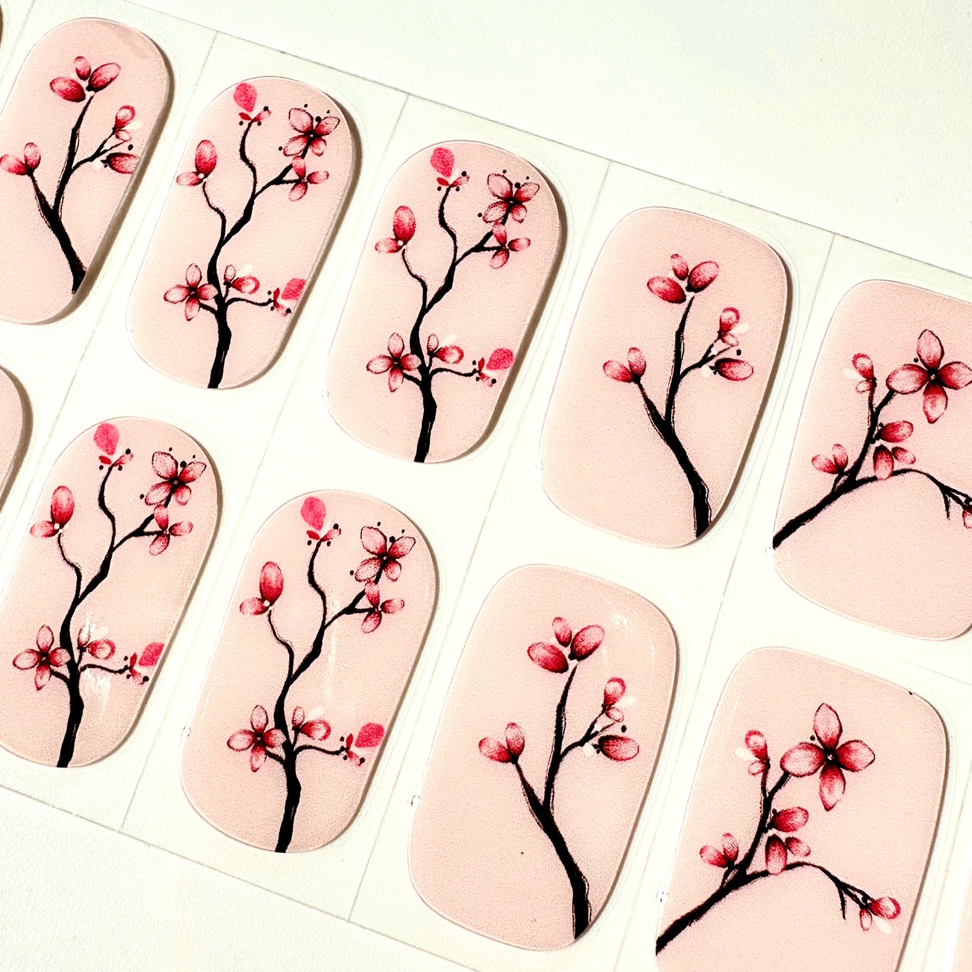 Close-up of pink cherry blossom gel nail wraps with botanical branch design