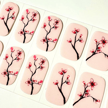 Close-up of pink cherry blossom gel nail wraps with botanical branch design