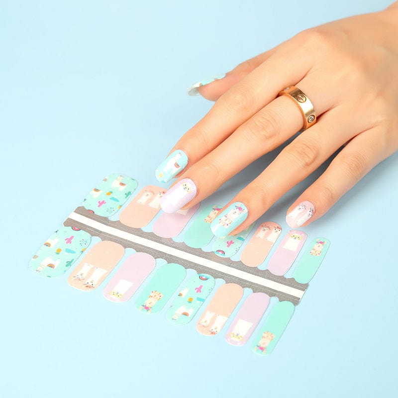 Hand applying colourful llama nail wraps with pastel pink and green designs